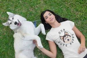 Husky t-shirt mockup of a woman lying on the grass with her husky dog