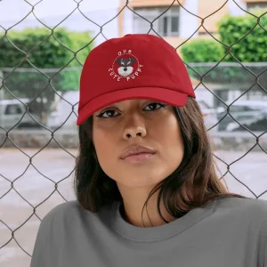 A woman wearing a Schnauzer dad hat by a chain-link fence